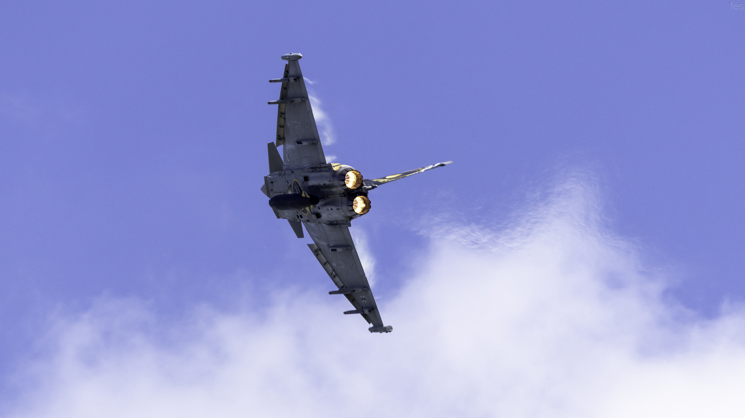 Underside of the Eurofighter Typhoon climbing on full afterburner among clouds