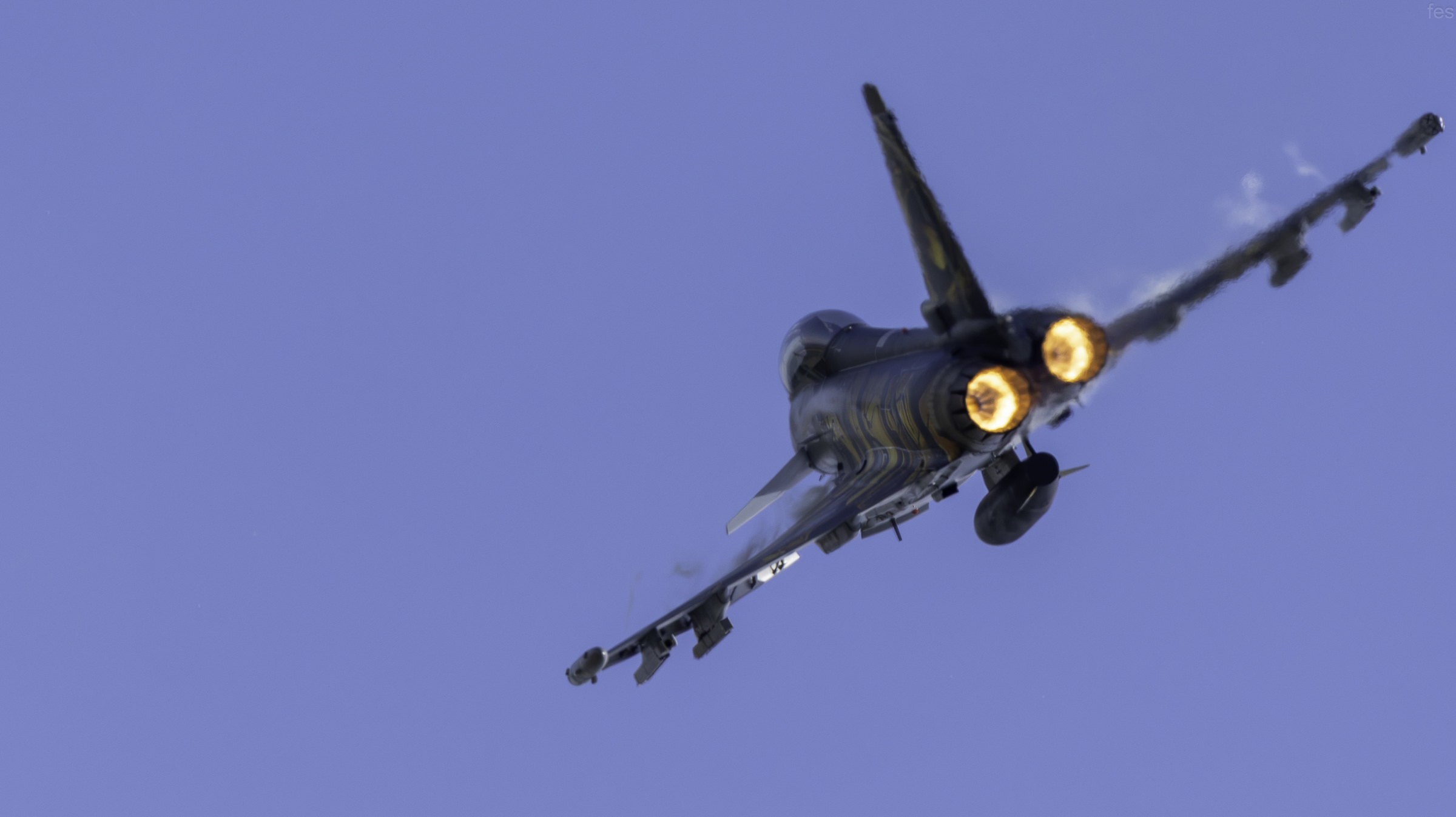Eurofighter Typhoon banking away with vapor streaming over the wings